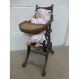 A late 19th Century/early 20th Century oak folding baby's high-chair/ walker with doll.