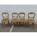 A set of four Edwardian balloon back dining chairs with upholstered padded seats raised on splayed