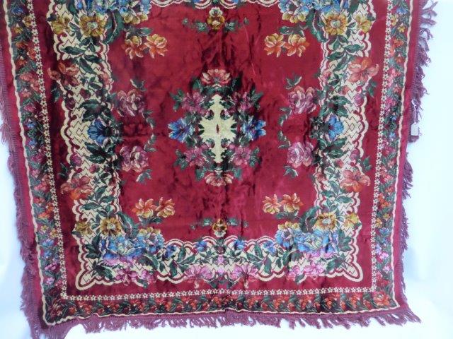 A square velvet table cloth with floral decoration.