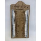 A wall mounted incised wooden shopping list with metal indicators to both sides.
