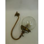 A brass gas lamp with glass shade.