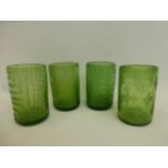 Four hand blown green glass tumblers with assorted etched designs.