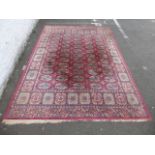 A room size floor rug with multiple medallions on a red ground with a repetitive medallion border,