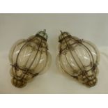 A pair of decorative bulbous glass and wirework hanging lanterns.