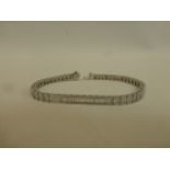 A platinum and diamond tennis bracelet of fifty-two links each containing three bagette diamonds,