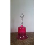 A Victorian cranberry glass decorative bell with glass clapper.
