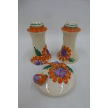 A pair of Clarice Cliff Newport Pottery Bizarre salt and pepper shakers and a pot lid in the