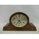 An inlaid mahogany oval faced mantel clock with Westminster chimes.