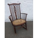 A stained wheel back rocking chair with cane seat.