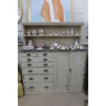 An Edwardian painted pine dresser of seven drawers flanking a cupboard, with plate rack over.