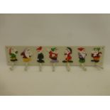 A cast metal coat/cup rack, each hook depicting one of the seven dwarfs.