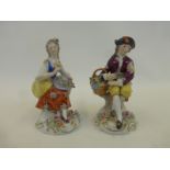 A pair of Sitzendorf porcelain figures depicting a seated girl and boy with flowers, on rococo style