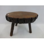 A naturalistic wooden tripod stool/table with bark finish.