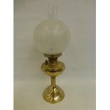 A brass oil lamp with etched glass shade and clear glass funnel.