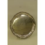 A small silver salver with gadrooned edge raised on three shaped supports, with inscription to the