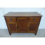 A 1920s oak sideboard, the central cupboard flanked by two drawers above two cupboards, with applied