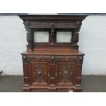 A Gillows oak mirror backed credenza, the upper section with all-over carved decoration depicting