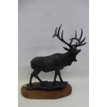 A cast metal figure of a standing stag on a wooden base.