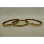 Three 9ct gold bangles with similar etched decoration, 19.4g.