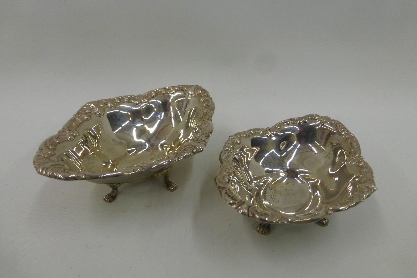 Two Birks sterling silver dishes raised on lion paw supports.