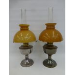 A pair of Alladin oil lamps with yellow mushroom shades and clear glass funnels.