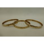 Three 9ct gold bangles with similar etched decoration, 18.9g.