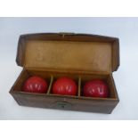 A leather cased set of three 19th Century/early 20th Century billiard balls (probably ivory).