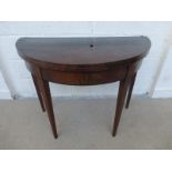 A George III mahogany and ebony strung demi-lune fold over card table raised on square tapering