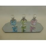 Three decorative glass scent bottles with a mittored stand.