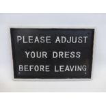 A cast metal "Please adjust your dress before leaving" wall plaque.
