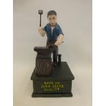 A cast metal John Deere money box depicting a blacksmith at work.