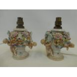 A pair of Continental ceramic lamp bases decorated with applied cherubs, assorted flowers and
