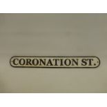 An elongated cast metal street sign inscribed Coronation Street.