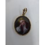 A miniature 19th Century portrait pendant depicting a young boy reading, possibly on ivory, cased in