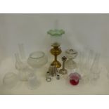 A collection of assorted glass light shades, glass funnels etc. also a brass oil lamp with
