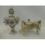 A continental ceramic twin handled lidded vase decorated with applied cherubs and encrusted with