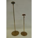 Two adjustable velvet topped hat stands raised on circular bases.