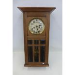 An oak cased 1920s wall clock with bevel edged glass door and German movement.