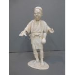 A 19th Century ivory figure of a man holding leaves and with chequered decoration to the jacket,