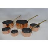 A set of six graduated copper and brass handled saucepans.
