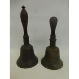 Two brass school bells with turned wooden handles.