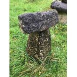 A staddle stone base with a block of stone on top.