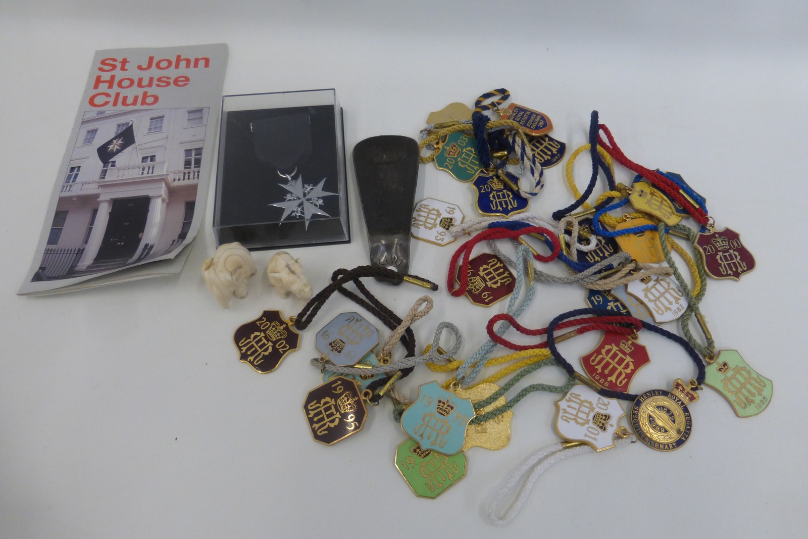 A quantity of enamel rowing badges, a St. John House Club medal, two carved ivory elephants and a