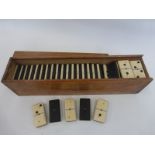A wooden cased heavy set of ebony and bone dominoes.