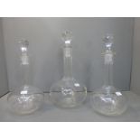 A pair of glass decanters and one larger similar.