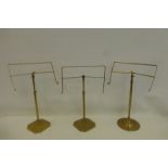 Three polished brass adjustable shop display stands by Harris and Sheldon of Birmingham.