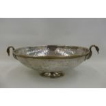 A silver plated on brass hand beaten twin handled table centre bowl, the handles in the form of