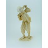 A 19thC Japanese carved ivory figure of a Man, carrying a basket over his shoulder, on shaped oval