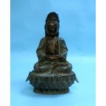 An antique Chinese bronze seated figure of Guanyin, with separate stand, 14in (35.5cm) high.