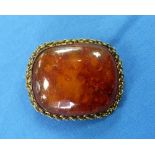 An oblong Brooch, the centre with a large piece of amber with a gilt metal ropework border and clasp